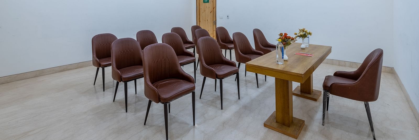 Front view of a conference room with a table placed between a chair and multiple chairs at DLS The Classio